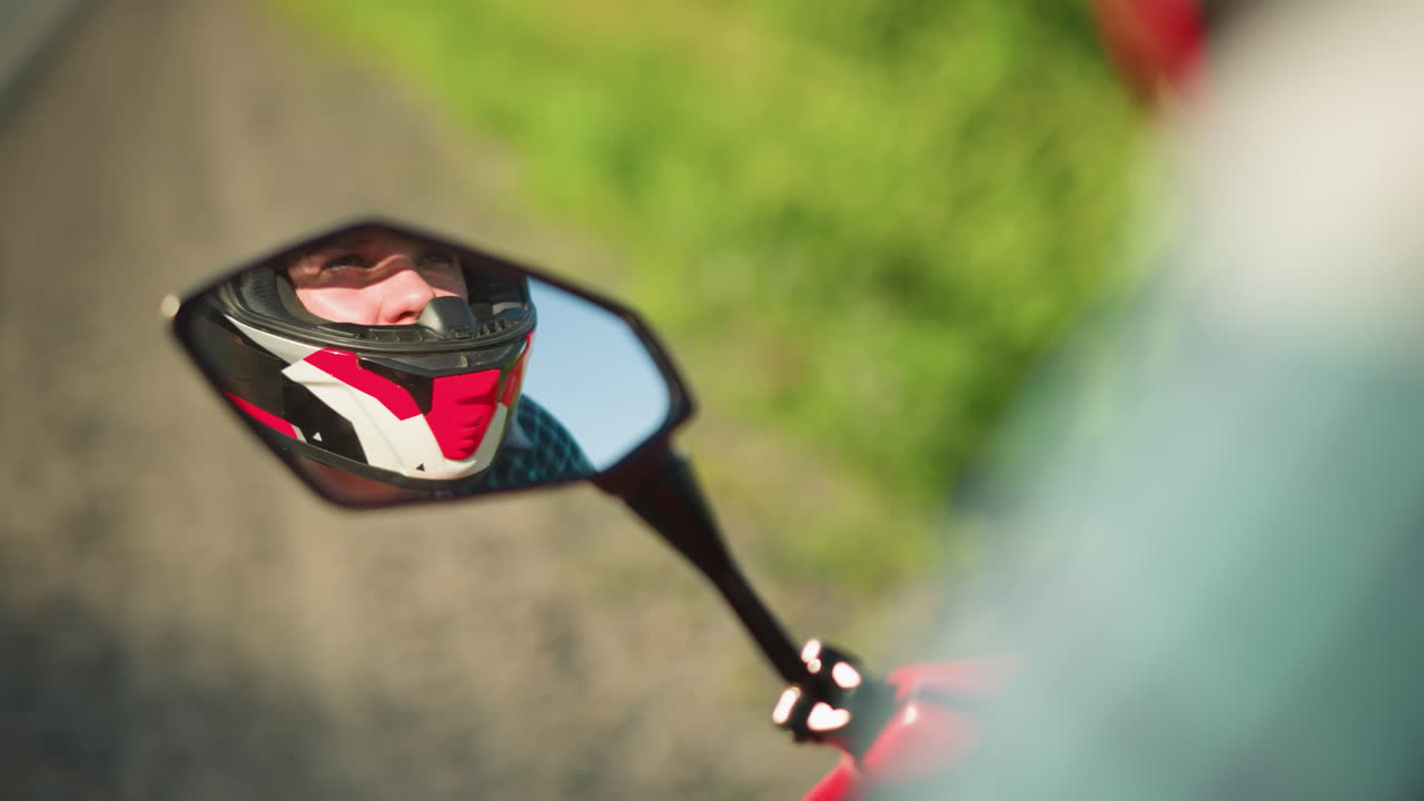 reflejo en primer plano de la cara de un motociclista visto a través del espejo de la motocicleta, con un casco, con un fondo borroso suave
