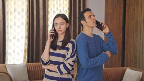 Serious-Indian-couple-talking-on-mobile-phones