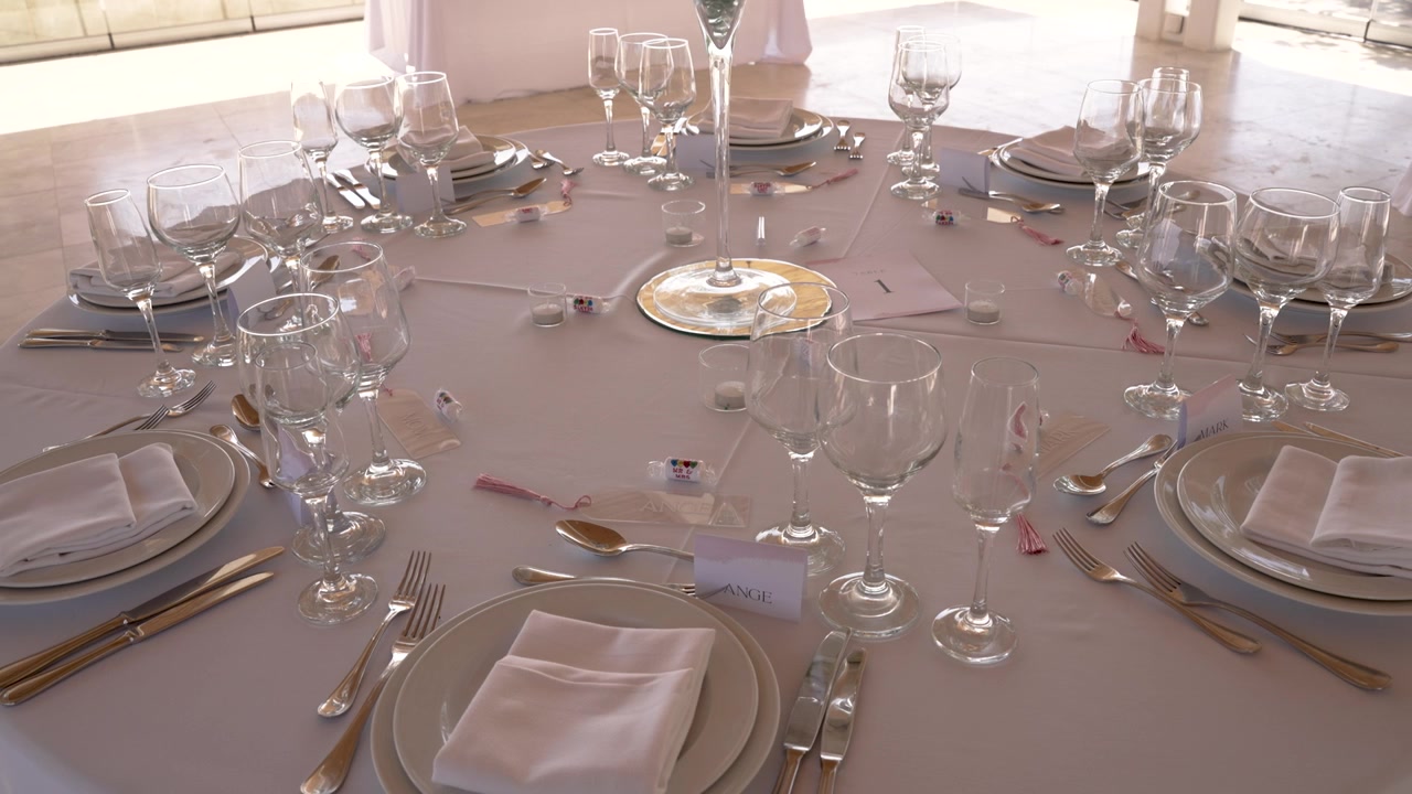 A beautifully arranged dinner table features fine China and crystal glassware. The setting is perfect for a memorable evening event in a stunning location at sunset.