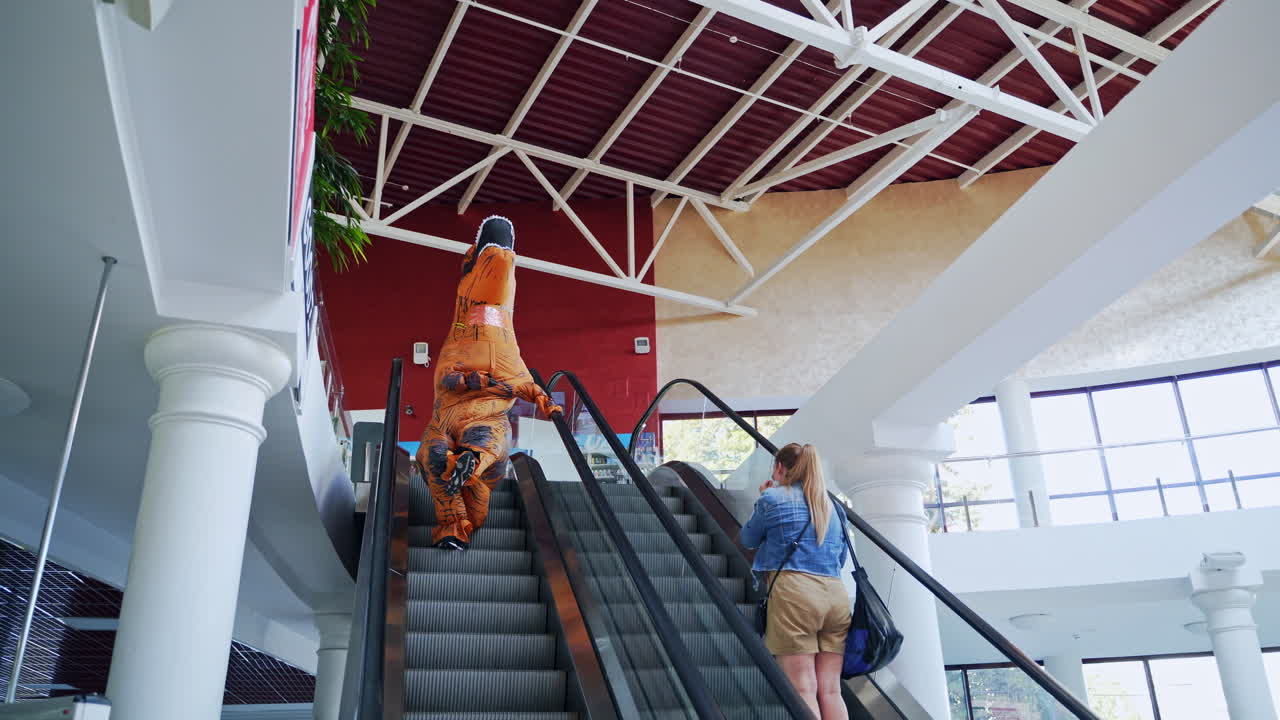 Person in a T-Rex Costume on an Escalator in a Shopping Mall