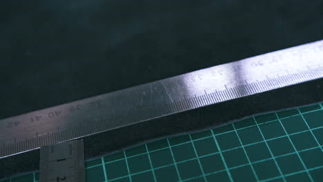 tailor measures leather cloth with metal rulers on board