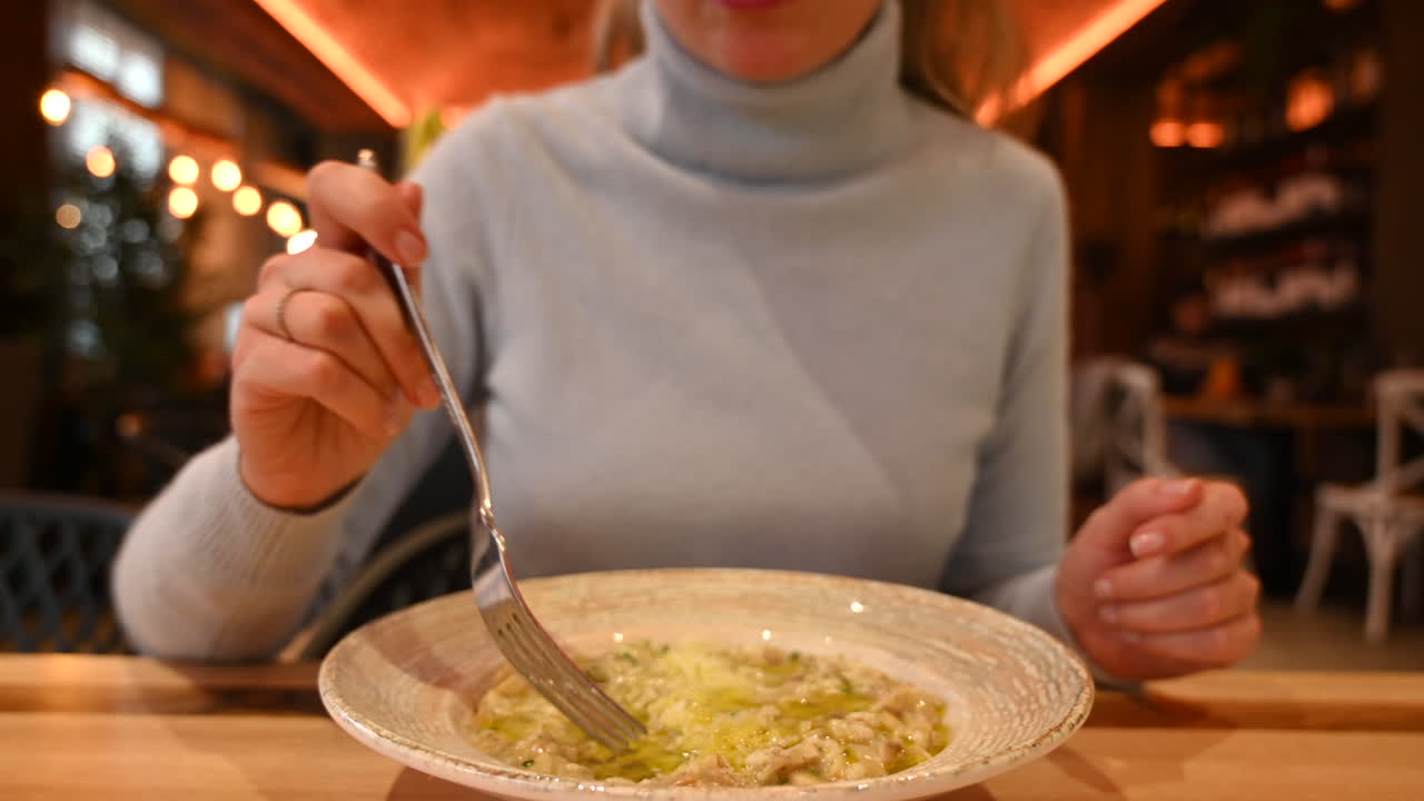 Woman eating risotto with mushrooms in a restaurant