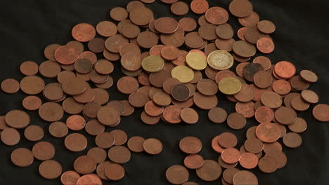 a hand pulling out 1 euro and cent coins that are placed on a dark cloth