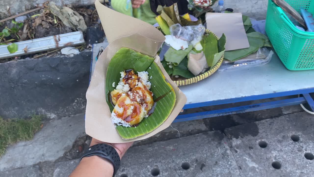 Penampilan lezat kue lupis yang dibungkus daun pisang segar langsung dari pedagang kaki lima tradisional.