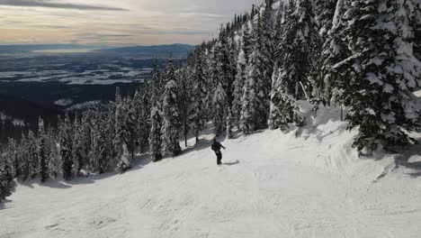 Ariel-Drone-Siguiendo-A-Un-Snowboarder-A-Través-De-Las-Montañas-Haciendo-Movimientos-Más-Lentos-Mostrando-Un-Hermoso-Amanecer-Tardío