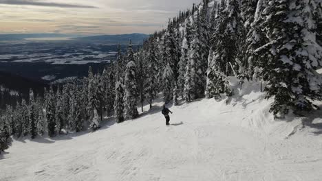 ariel drone siguiendo un snowboarder a través de las montañas haciendo movimientos más lentos mostrando un hermoso amanecer tardío