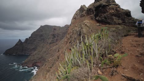 Female-hiker-at-the-edge-of-a-mountain-with-panoramic-view-over-the-ocean