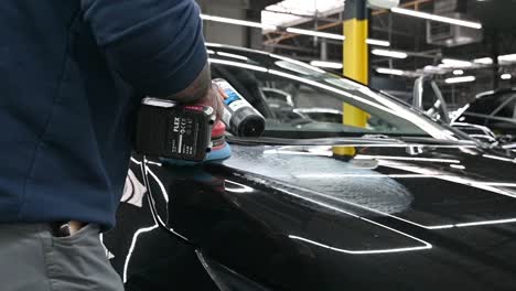 Garage-worker-polishing-black-hood-of-modern-vehicle,-close-up-motion-shot