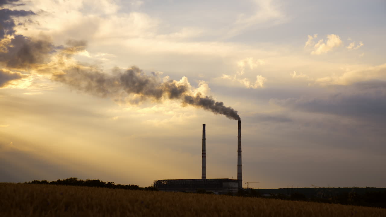 Two plant pipes hovering above the industrial zone. One of the pipes produces heavy smoke.