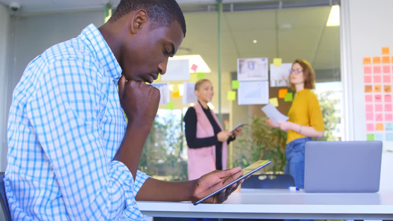 Side view of young black male executive working on digital tablet in modern office 4k