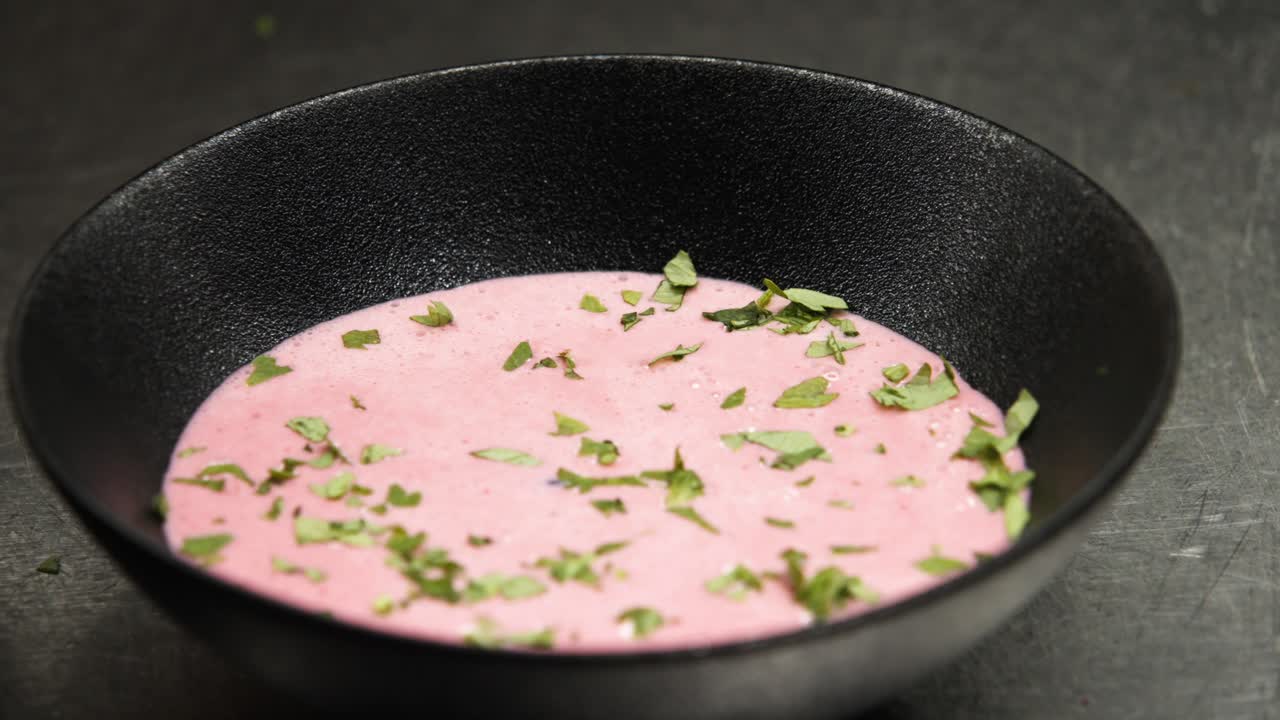 primer plano del chef adornando la sopa con hierbas en la cocina
