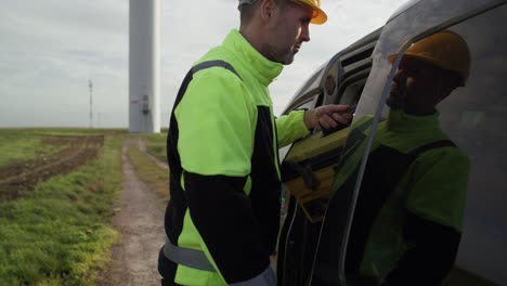 caucasian male professional came to field with windmill with tool box.