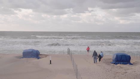 children running on beautiful windy beach in de haan, belgium - wide, slow motion