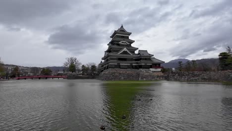 old japanese castle in front of the water being reflected in the water