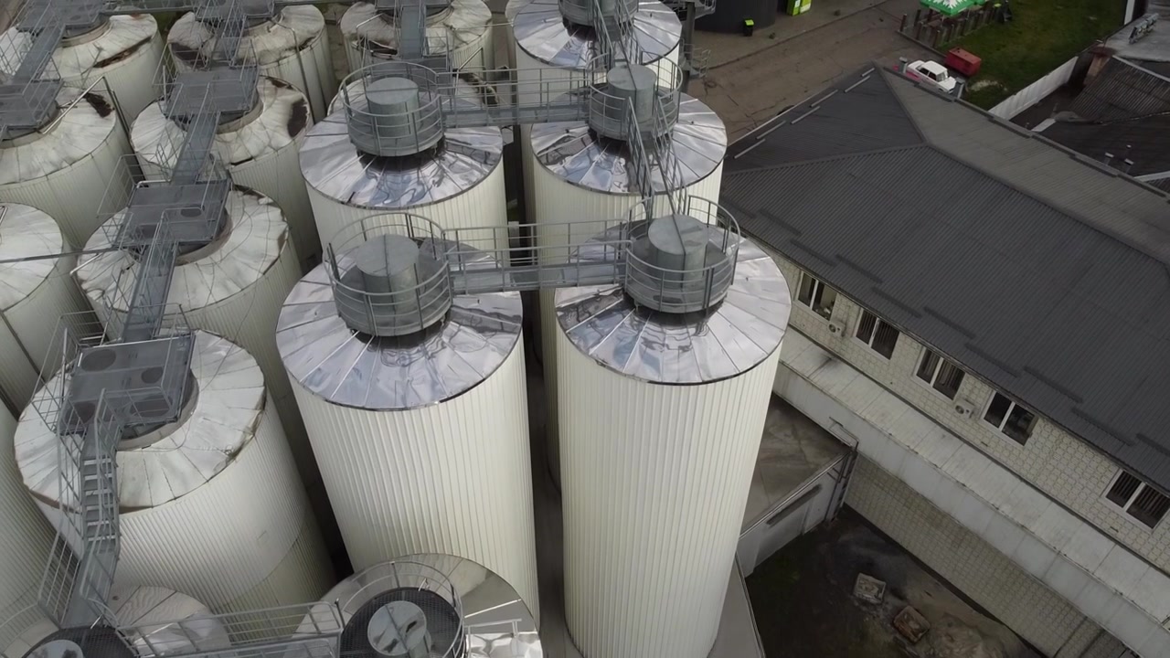 Aerial view of a drone flying over the beer production plant, several rows of tanks.
