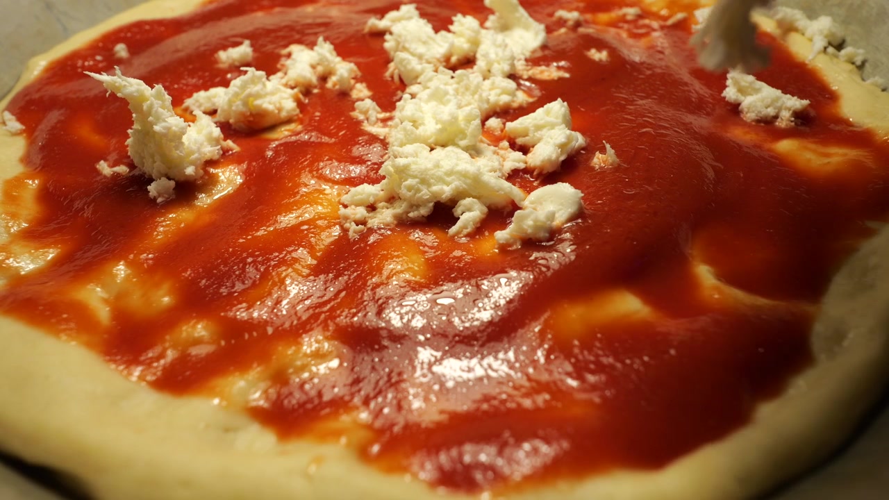 Primo piano di mozzarella fresca che viene adagiata su una pizza