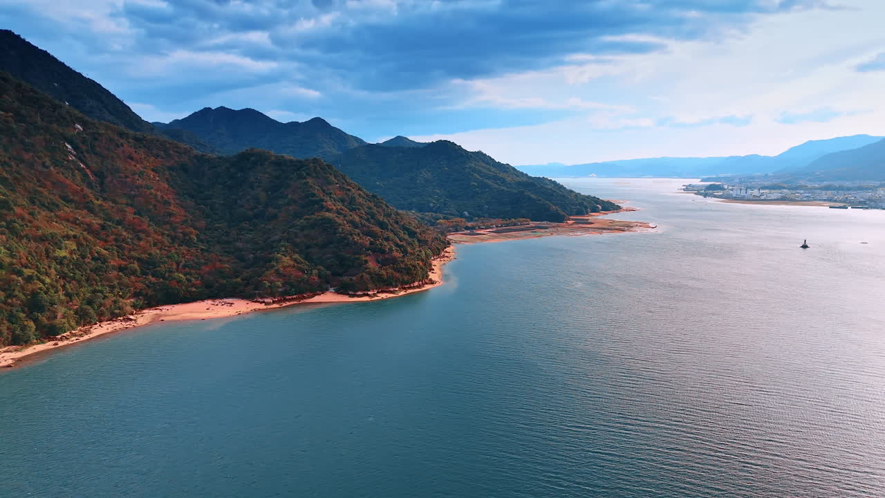 Flight over the calm waterscape along the wooded mountains. Spectacular view of the rocks under dark cloudscape from drone.
