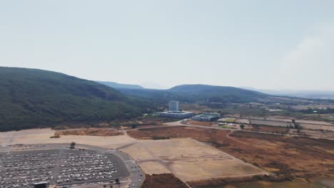 aerial panning shot of akron stadium in scenic area with green hills and city of guadalajara in background during sunny day - panorama view
