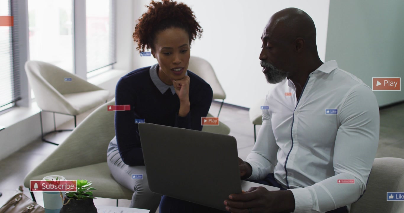 Peers leaning in lounge, man scrolling laptop, reviewing marketing Subscribe Play icons over scene