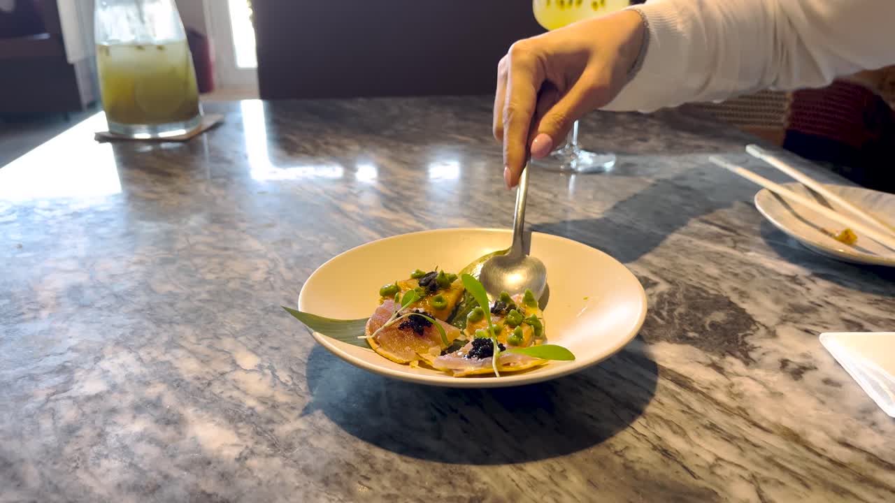 Serving fresh fancy small bite tapas in a plate with hand and fork, tasty European coastal food scene at table