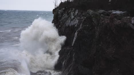 stormy waves crash against granite coastal rocky cliffs in slow motion