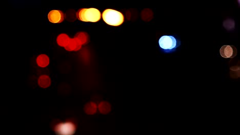 los círculos de bokeh en movimiento de las luces de los coches que corren por las calles de la ciudad. el fondo borroso de la ciudad, el tráfico nocturno.