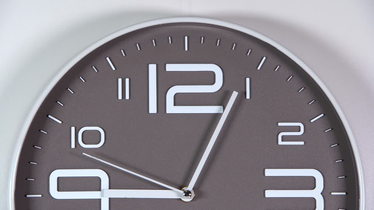 reloj de pared en un fondo gris. 09:05