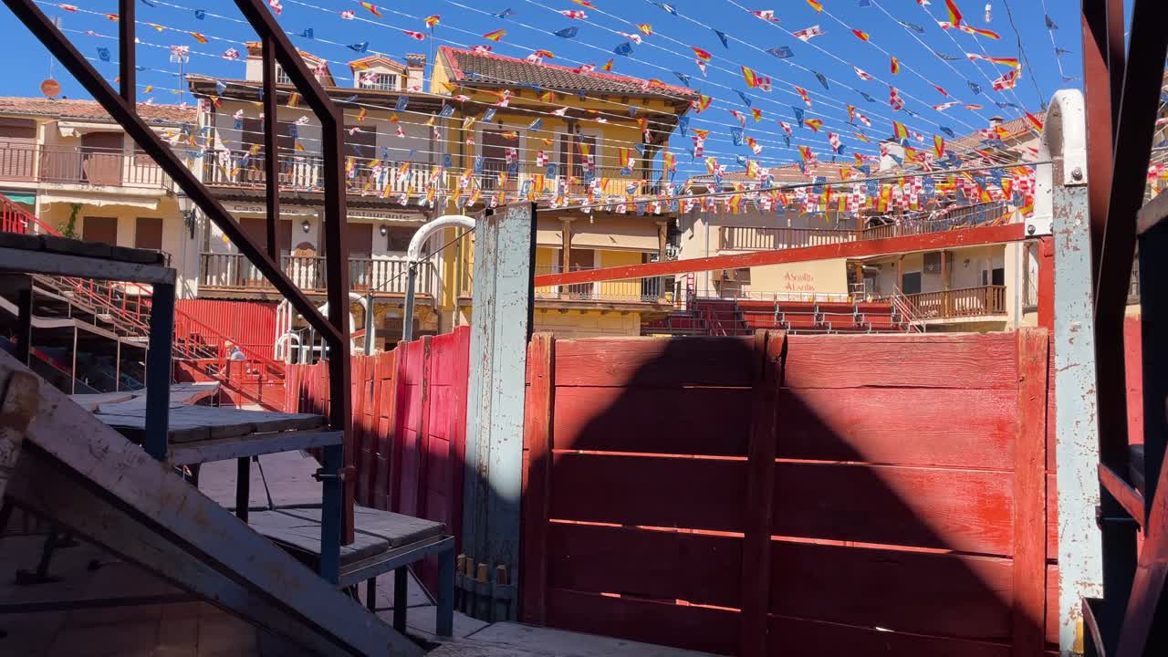 filming the interior of a mobile bullring installed in a public square in a town, we appreciate the wooden seats and the square is decorated with many flags for the occasion