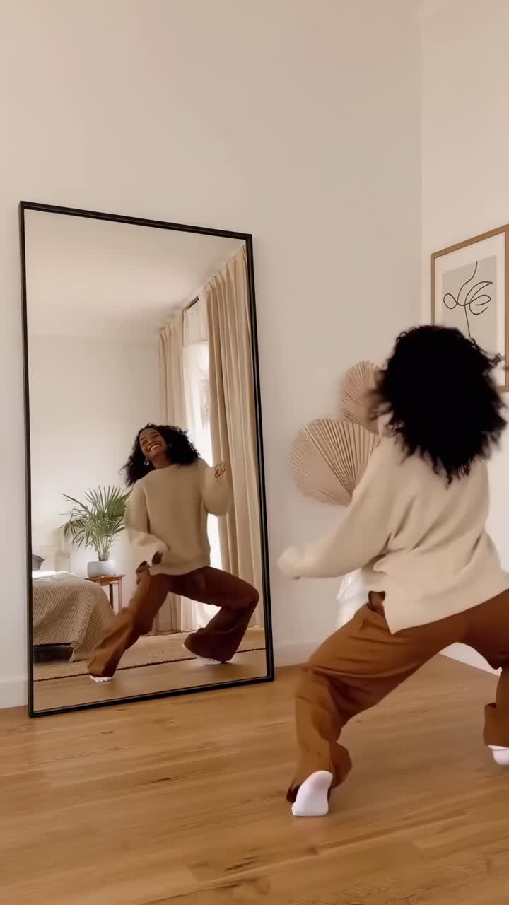 Video amatoriale di una donna in abiti comodi, a metà piroetta, ripresa da un angolo laterale in una stanza moderna