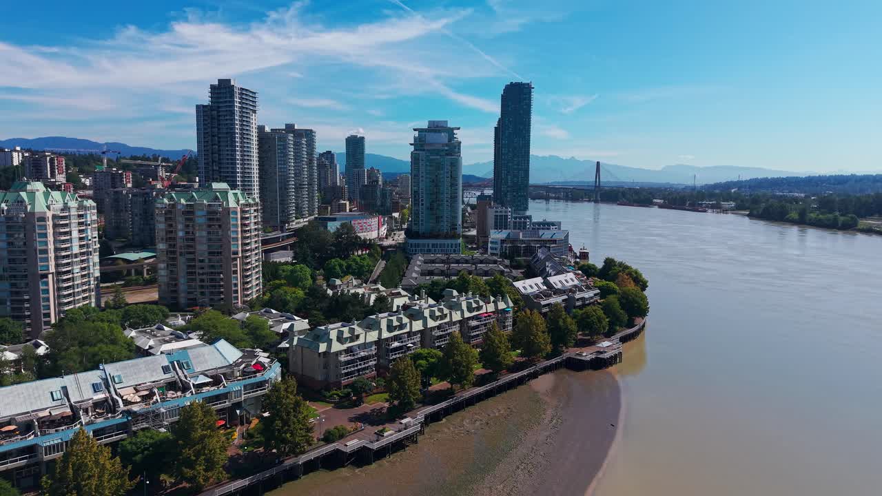 Filmato aereo realizzato con drone dello skyline del lungomare di New Westminster lungo il fiume Fraser, che mostra edifici multipiano, curve del fiume e cielo azzurro in British Columbia