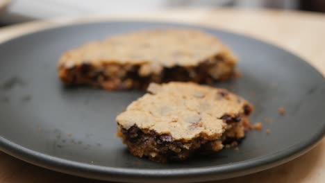 closeup of two chocolate chip cookies on a black plate