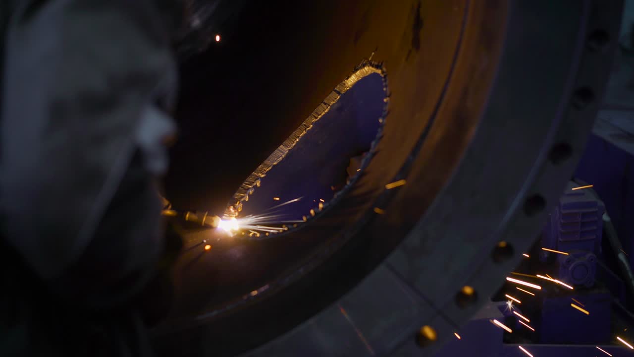 рабочий в тяжелой промышленности режет огромную трубу. рабочий шлифователь режет металл на заводе.