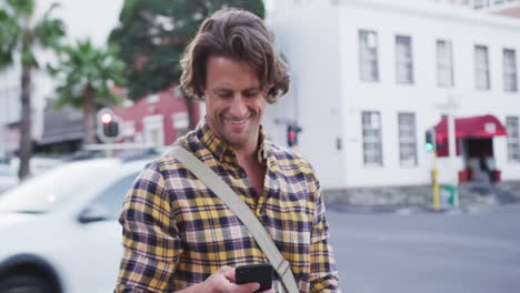 Kaukasischer-Mann-Lächelt-Und-Benutzt-Sein-Telefon-Auf-Einem-Fahrrad-In-Einer-Straße