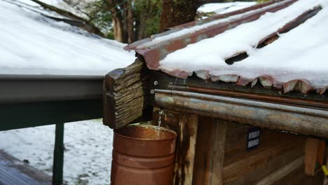 Water-flowing-from-a-an-old-gutter-into-a-rustic-downpipe-on-an-old-building-during-rain