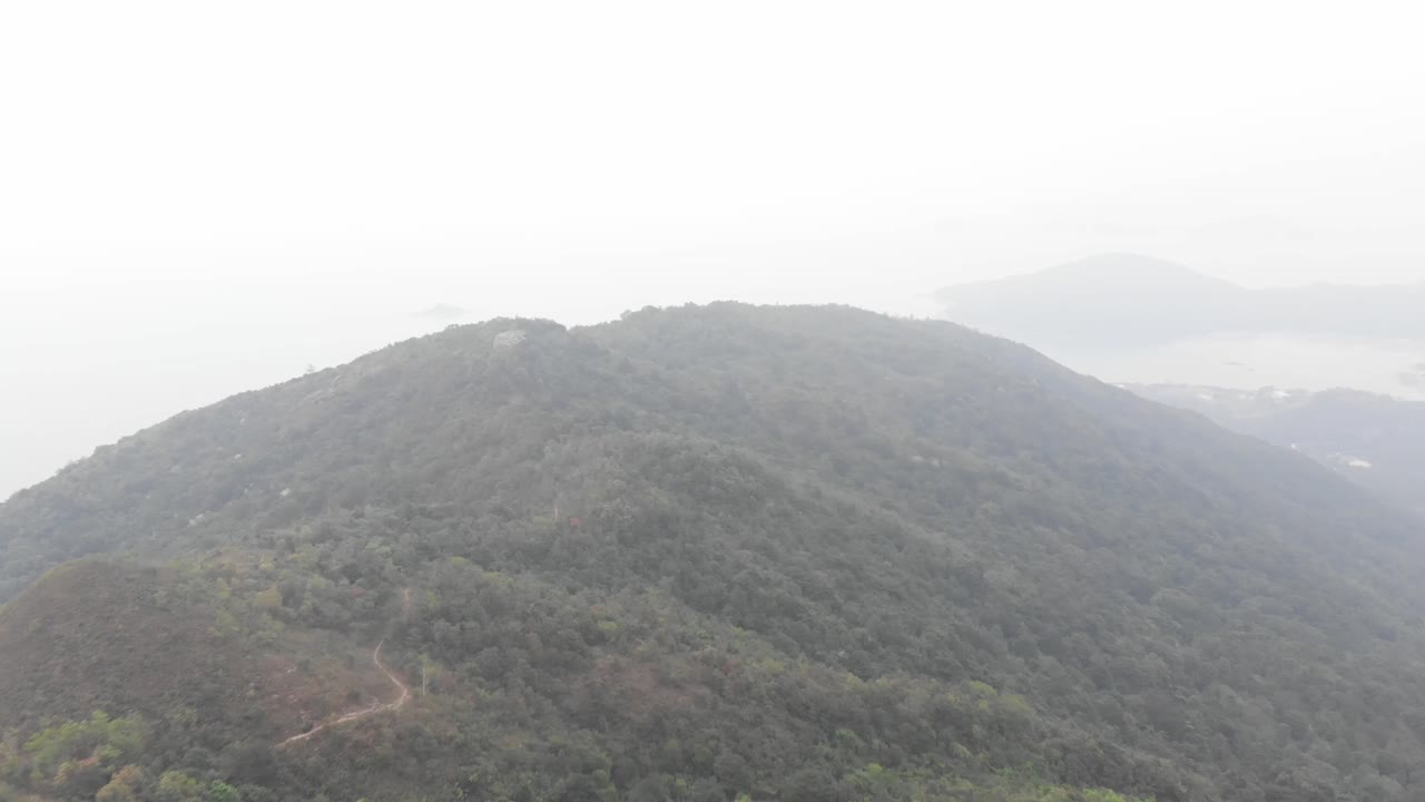 High altitude drone pan and tilt shot of a misty mountain.  Lan Tau Island.