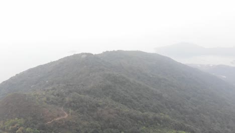 high altitude drone pan and tilt shot of a misty mountain.  lan tau island.