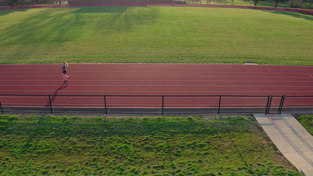 10대 소녀 선수가 일몰 카메라가 멀어지는 트랙에서 몸을 풀다