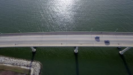 vista de pájaro mirando hacia un puente sobre el río mientras una gaviota y un coche pasan por debajo