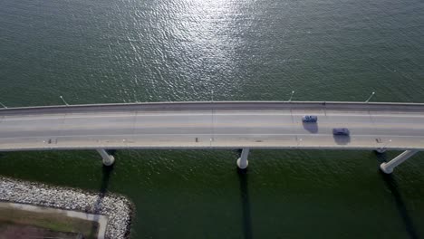 birds eye view looking down at a river bridge as a seagull and a car past below