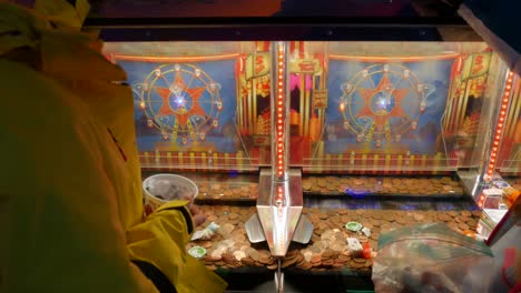 Dos-Niñas-Jugando-En-La-Máquina-De-Solt-De-Empujador-De-Monedas-En-Un-Casino-Arcade