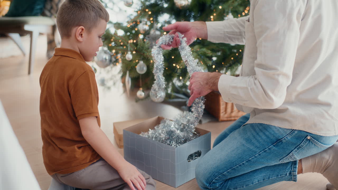 아빠와 그의 어린 아들은 크리스마스 트리 앞에서 크리스마스 장식품을 풀고