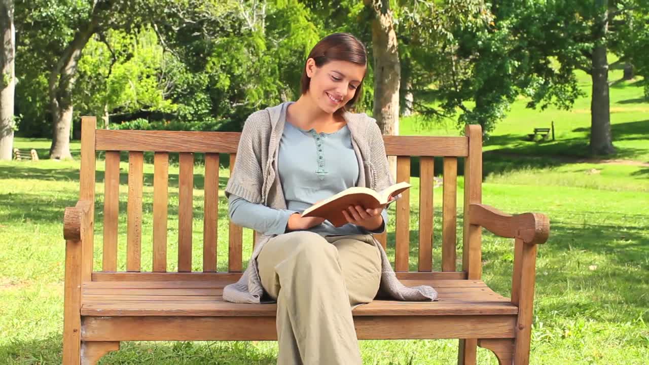 Young woman reading a book on a park bench