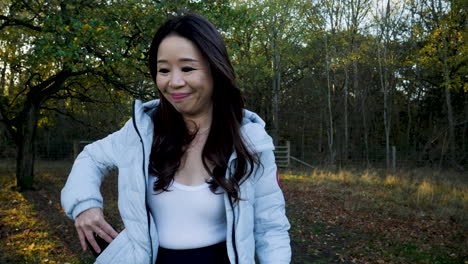 an asian woman texting on her phone in a field