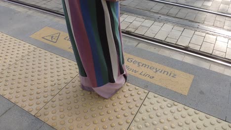 woman wearing striped pants at a tram station