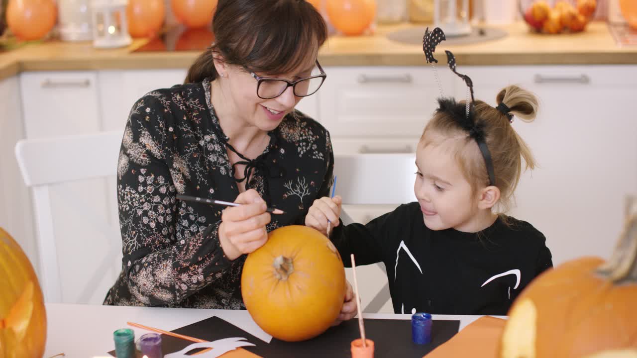 mujer y niña pintando calabaza