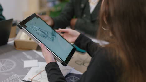 Jóvenes-Ingenieros-Desarrollando-Prototipos-De-Bicicletas-Usando-Una-Tableta-Viendo-Un-Diseño-3d-En-Un-Dispositivo-De-Pantalla-Táctil-Intercambiando-Ideas-Sobre-El-Desarrollo-Futuro-Colaborando-En-Una-Oficina-Creativa