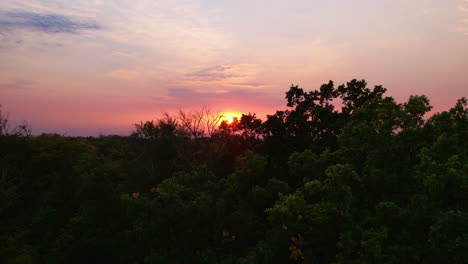 sunset over woods and trees next to a small village in germany - saxony - droneshot