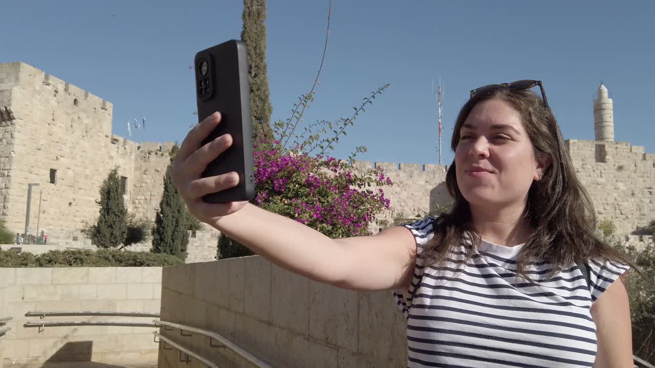 mujer tomando una selfie frente a las murallas de la vieja ciudad de jerusalén
