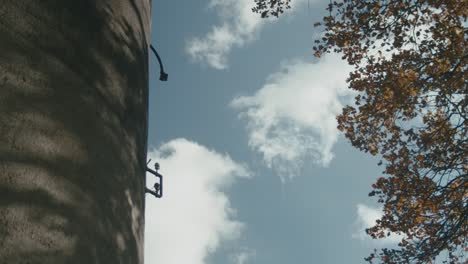 Timelapse-Of-Clouds-Going-Past-Next-To-Cylindrical-Concrete-Structure-And-Autumnal-Trees