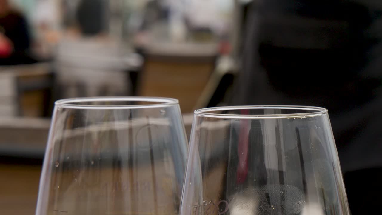 Primo piano di bicchieri di vino bianco sul tavolo di un bar all'aperto, luce naturale, profondità di campo ridotta